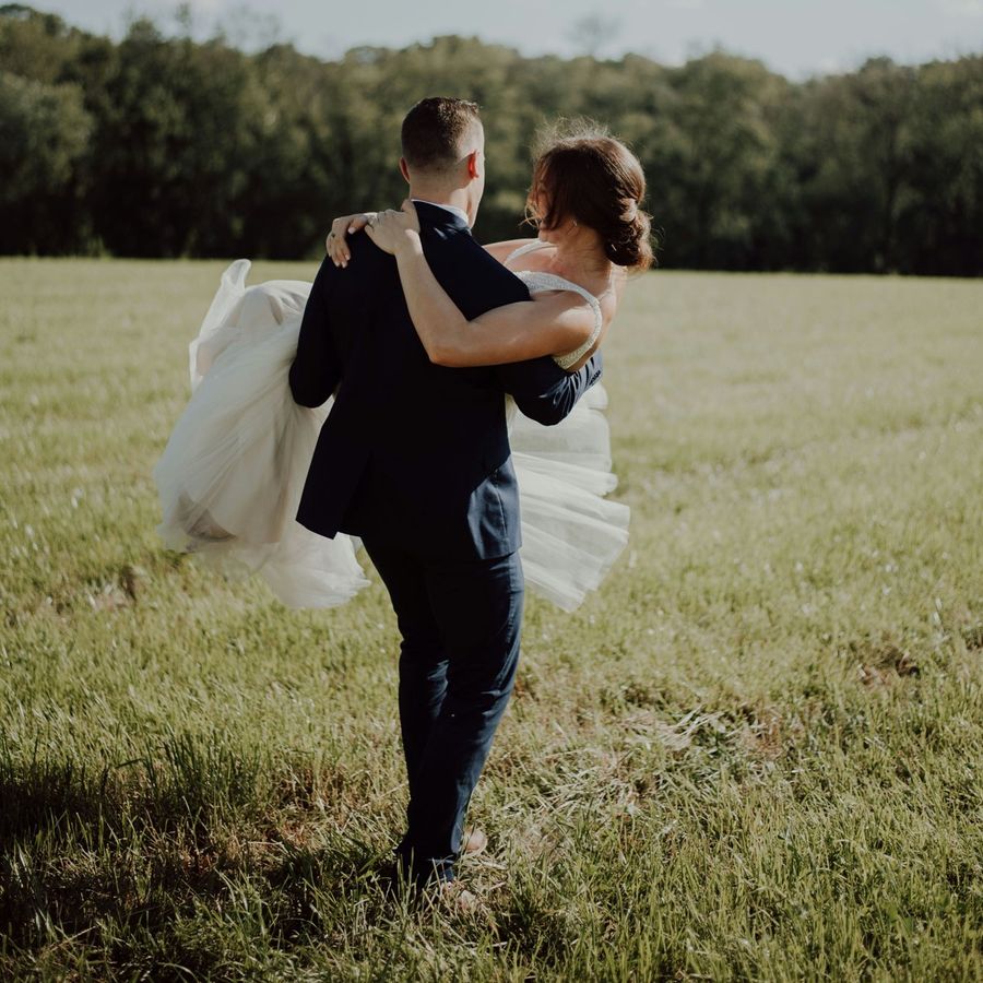Le marié portant la mariée dans un champ